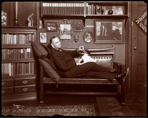 Will R. Barnes liggend op een bank met een hond in zijn bibliotheekstudio
